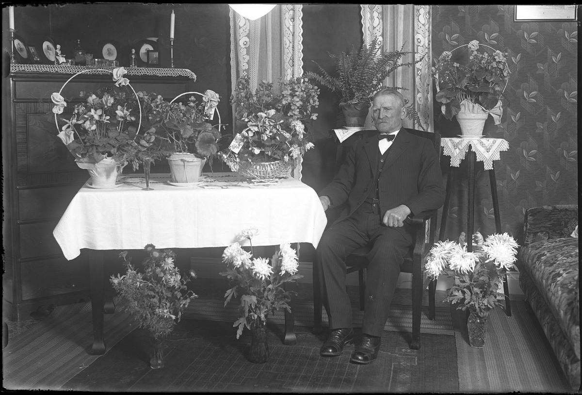 Alfred Andersson fotograferad i ett finrum omgiven av blommor i samband med sin 75årsdag.