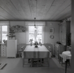 I köket på gården Sunnanåker finns ett köksbord och ett kylskåp samt väggprydnader, januari 1970.