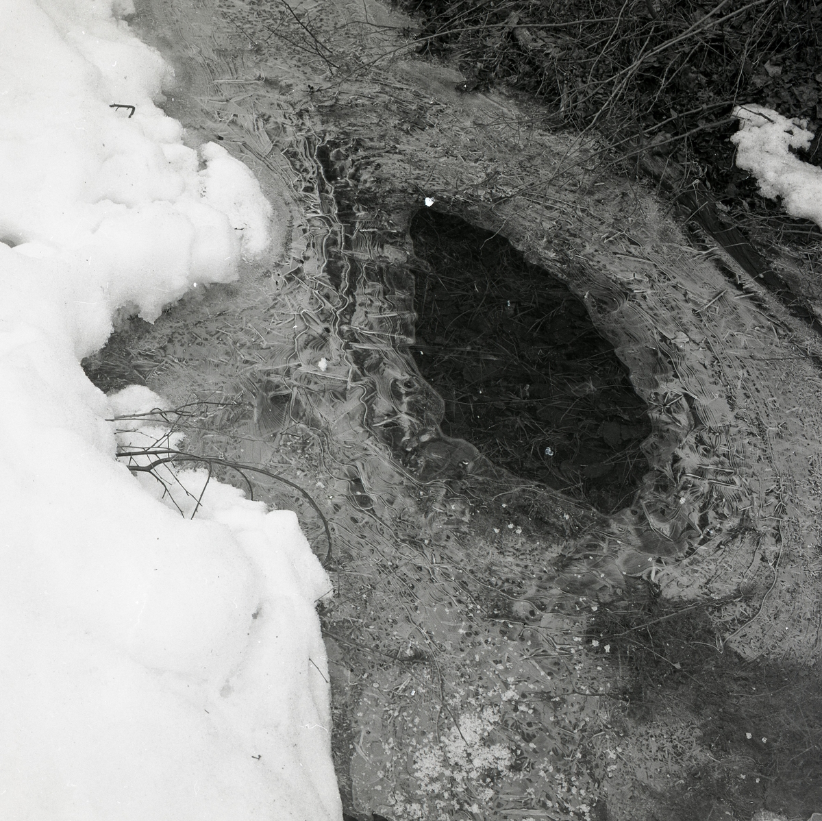 En öppning i ett islager avtäcker marken under snön, 19 april 1978.