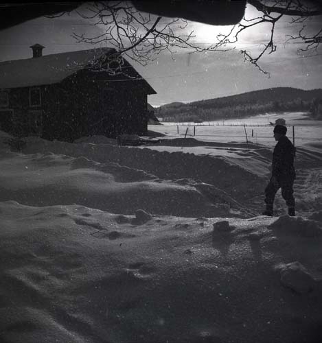 En man går mot ett hus genom ett snöigt landskap, 1948.