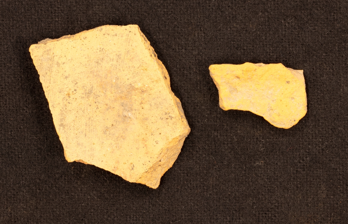 Fragment en skärva av lergods. Gulgrön glasyr. Två parallela, gula sträck med vågor som krokar i varandra i mellan sträcken.

Funnen i anläggning S9.
Grävningsledaren ändrade sedan anläggningsbeteckningen i grävrapporten till K9.
Fynden kommer från en arkeologisk utgrävning/schaktövervakning av Brätte 1:8 ledd av Oscar Ortman 2018.