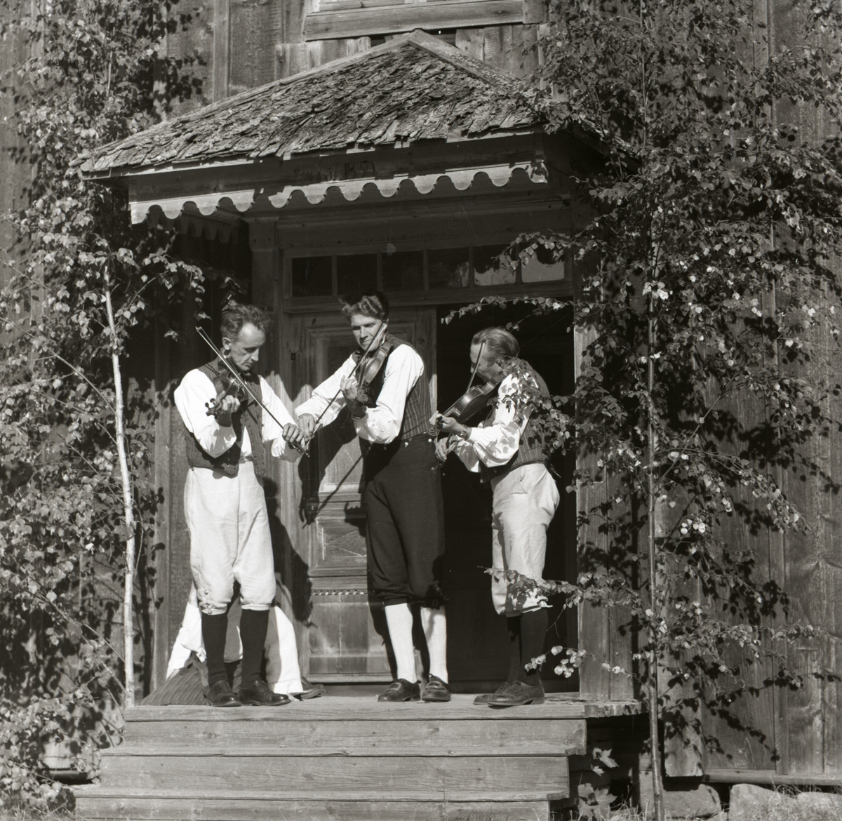 Tre spelmän med fiol underhåller vid hembygdsfesten i Rengsjö, 28 augusti 1955. De är klädda i folkdräkter.