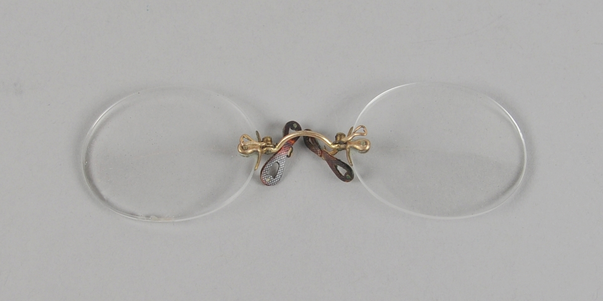 To brilleglass festet sammen med nesebøyle av metall.