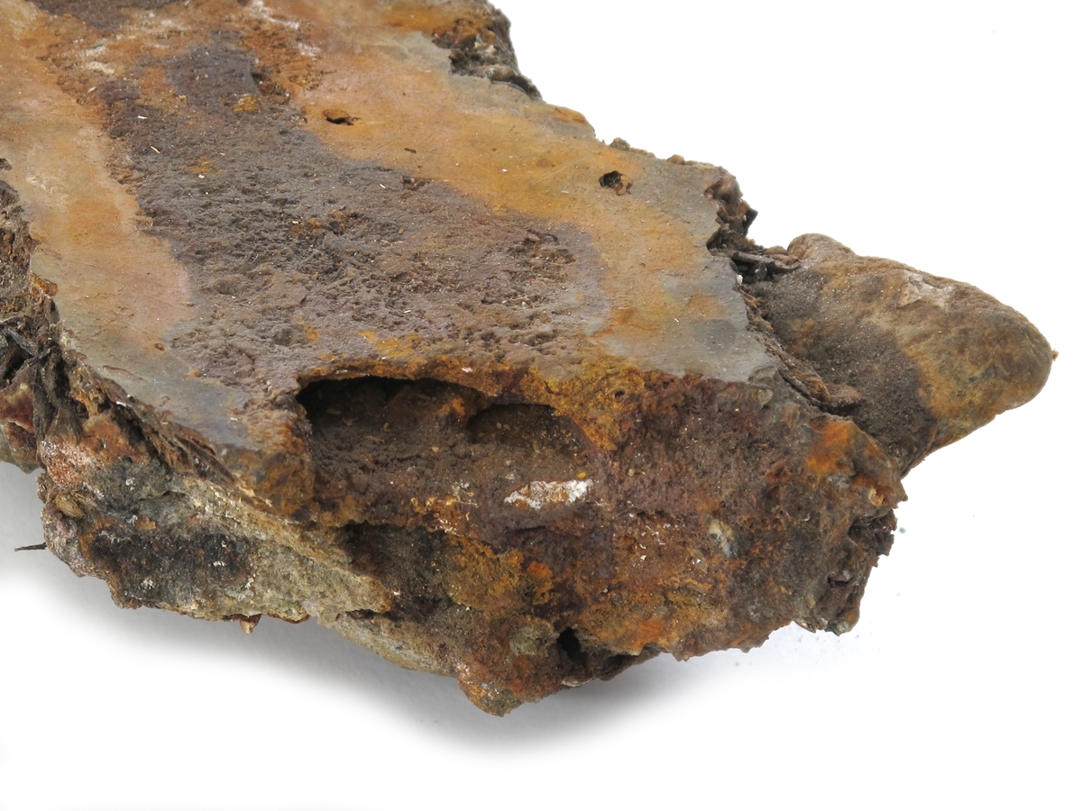 Korrosjonklump f) 
Korrosjonsklump omkring et stykke jern. Består av jern, rust, stein, sand og uidentifisert materiale.