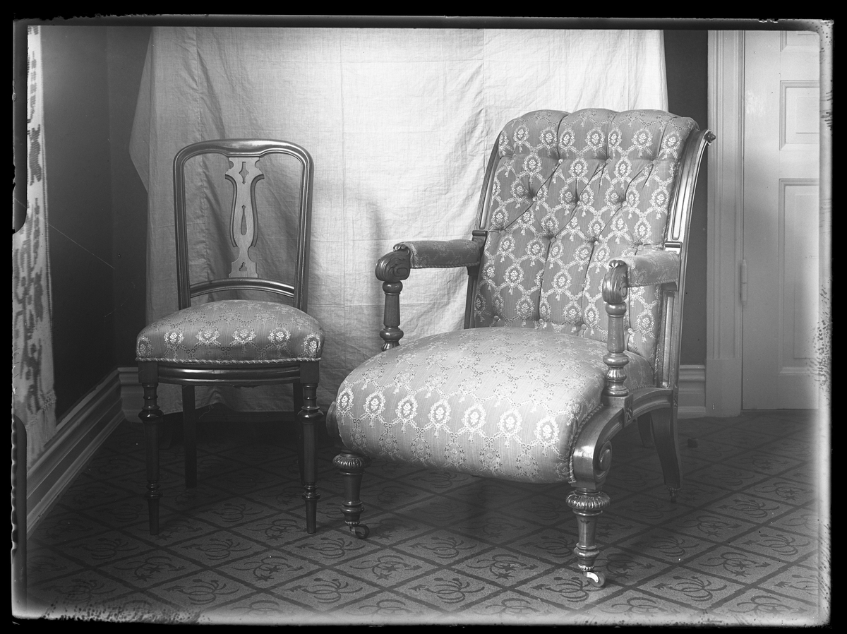 En stoppad armlänstol samt en stol med klädd dyna. I fotografens anteckningar står det "Stolar för hr. Petersén".