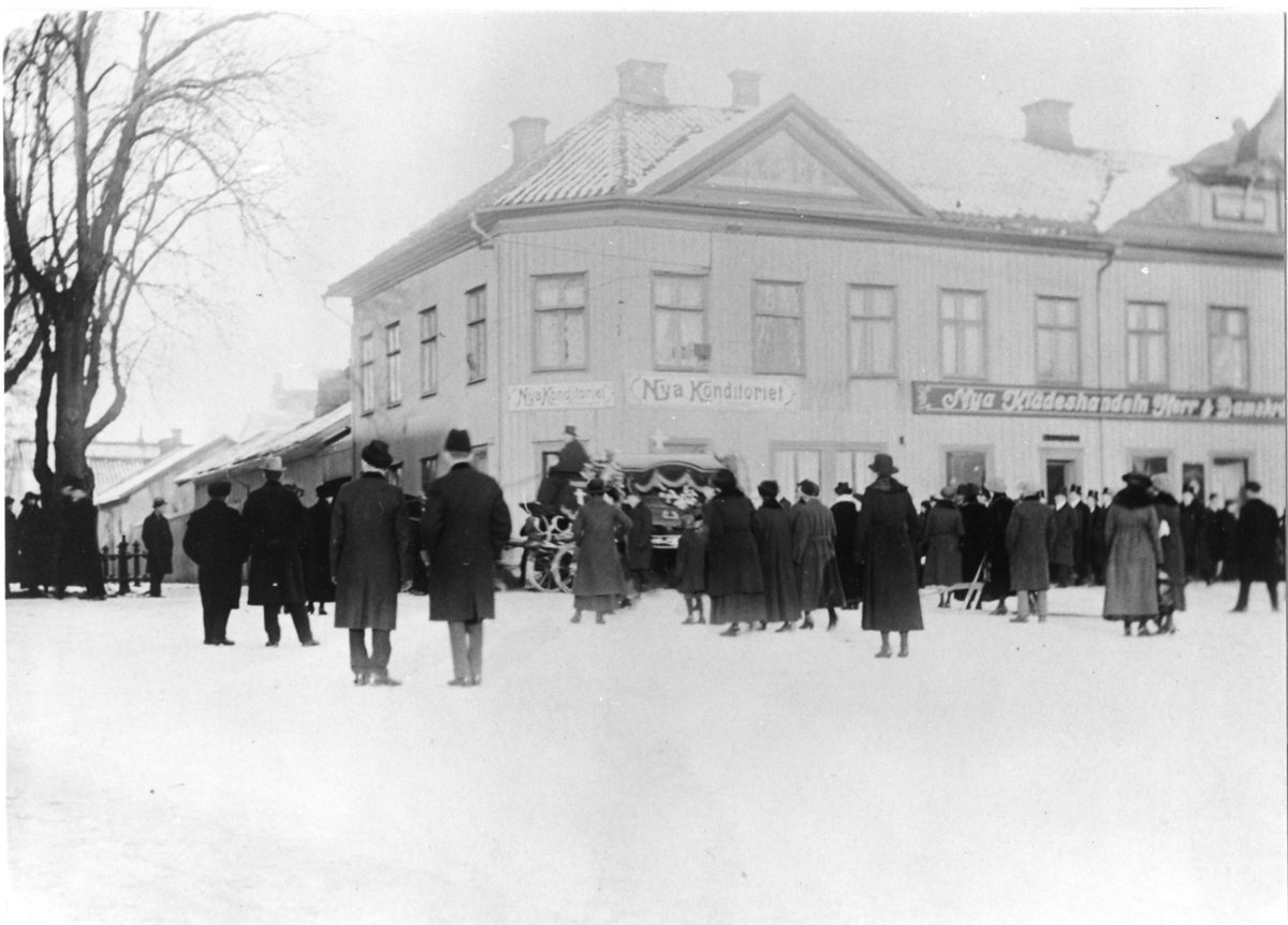 Ett begravningståg med droska i spetsen passerar Stora Torget vintertid.
Hörnet av Kungsgatan och Östra Kyrkogatan.
