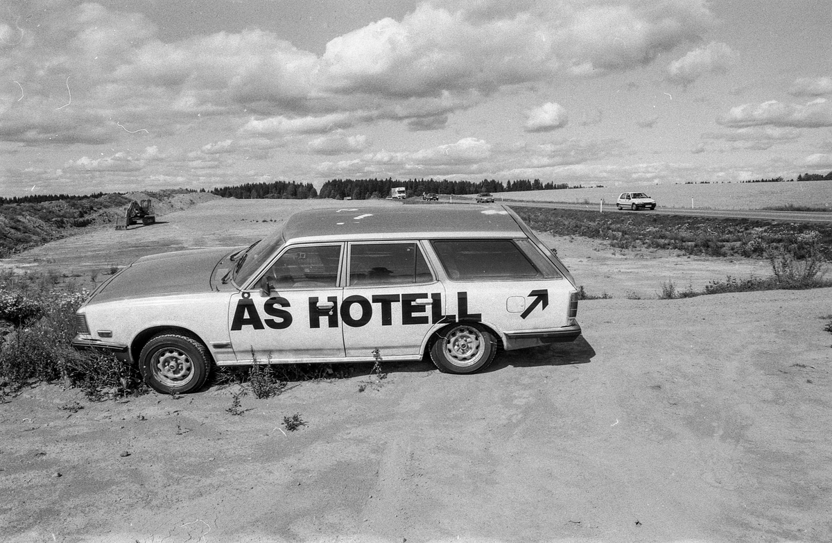Biler påmalt reklame for Vestby Hotell parkert på et jorde.