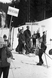 Ungdom med ski samlet rundt mange plakater med forskjellige 