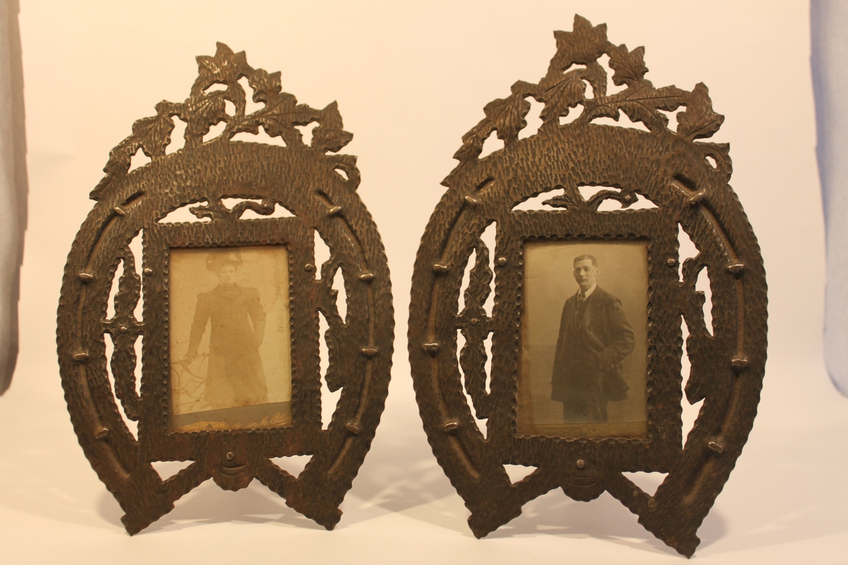 Två fotoramar i  hamrad järnplåt i form av en hästsko med söm. Krönta av bladornament och med en glasad ram innanför "hästskon". I den ena ramen sitter ett fotografi av en man och i den andra ett fotografi av en kvinna. Båda i kläder från sekelskiftet 1900.