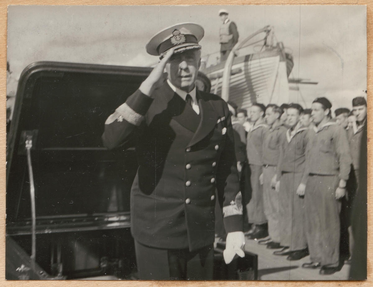 Chefen för marinen viceamiral Strömbeck inspekterar Fylgia. Han utför en militär hälsning framför manskapet som har tagit uppställning på däck.