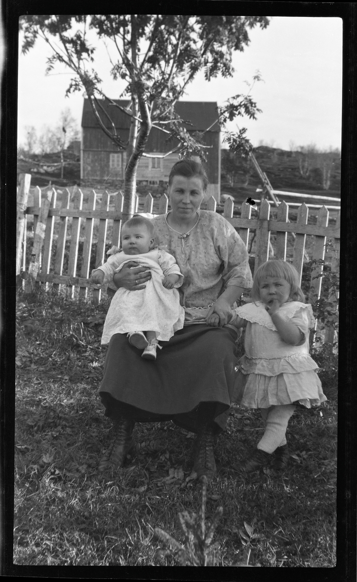 Gruppeportrett av kvinne og to barn i hage.