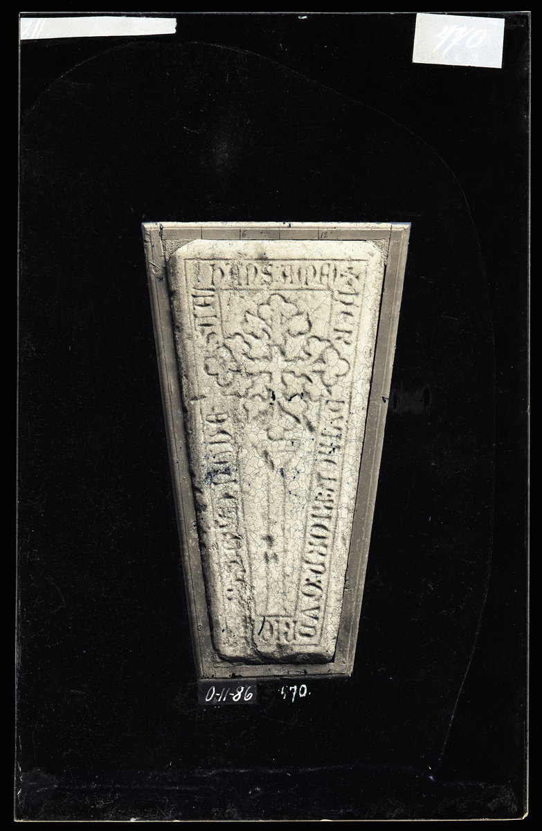 Middelaldersk (1300-1350) gravstein fra Nidarosdomen. Organisk kors, innskrift langs kanten. 

Tekst: + HER : HVILER : BIORN : GVRIC(K)SUN : GVD : HAUE : SAAL : HANS : AMEN

"Her kviler bjørn Gudriksson, måtte Gud ha sjela hans, amen"