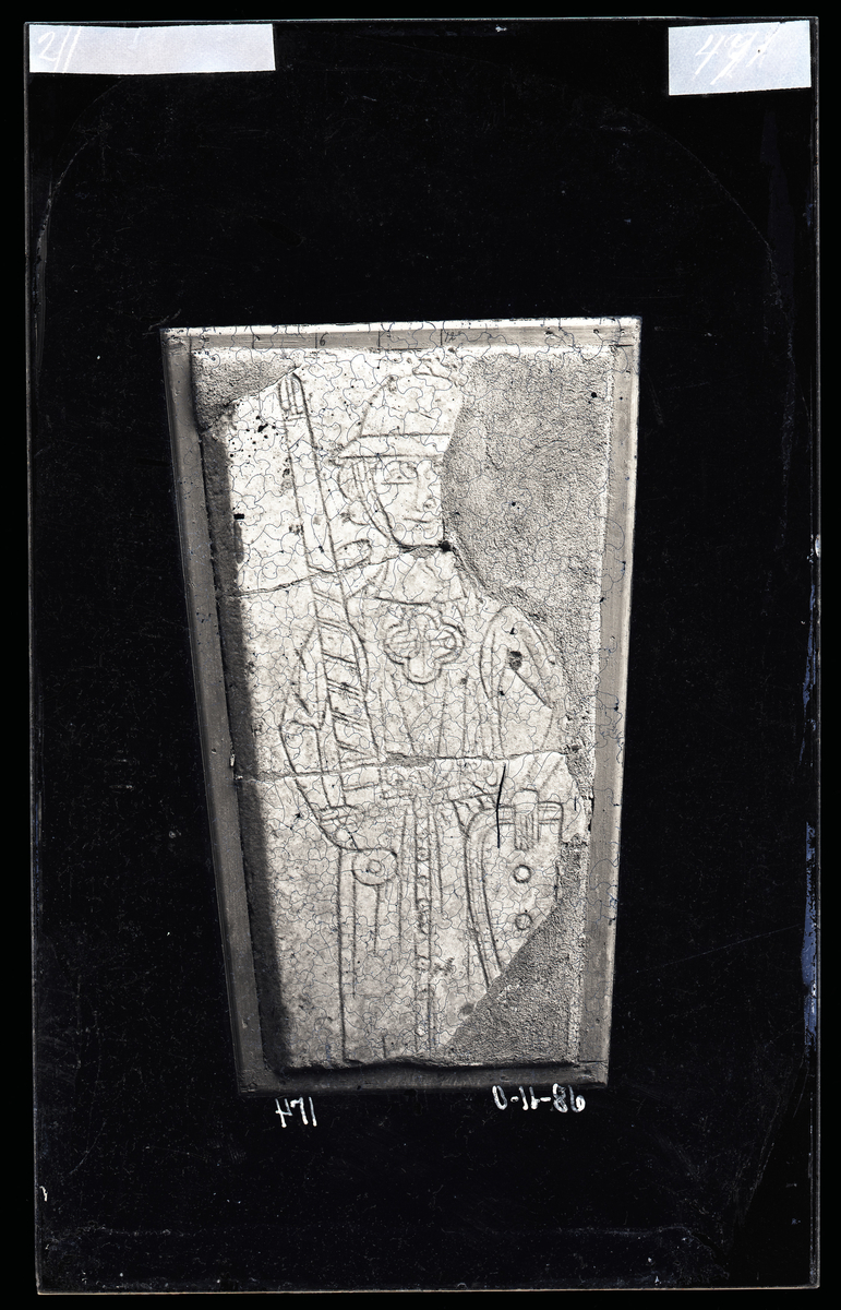 Middelaldersk (1250-1300) gravstein fra Nidarosdomen. Ridder kledd i skjorte med trange ermer og kjortel uten ermer. Tekst på steinen:

+ HER : HVILIR : B(IORN) : FINS : SON : R(IDDARI)

"Her hviler Bjørn Finnson riddar"
