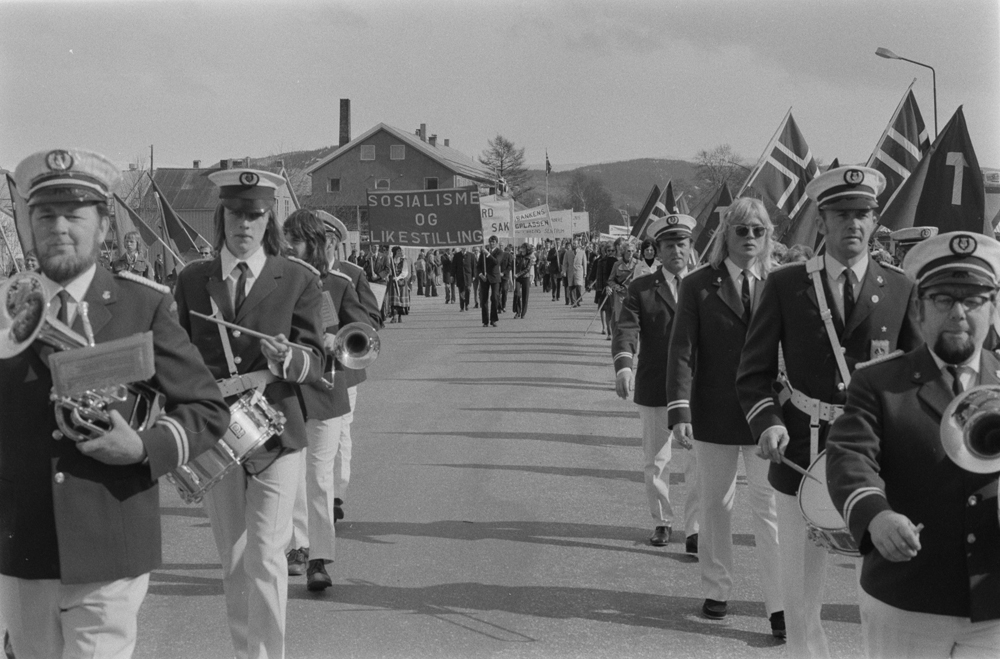Hornmusikken Fram. 1.Mai-tog i Mosjøen 1975, demonstrasjonstog i Elvegata. Kinokrysset. Bondehandelen i bakgrunnen.