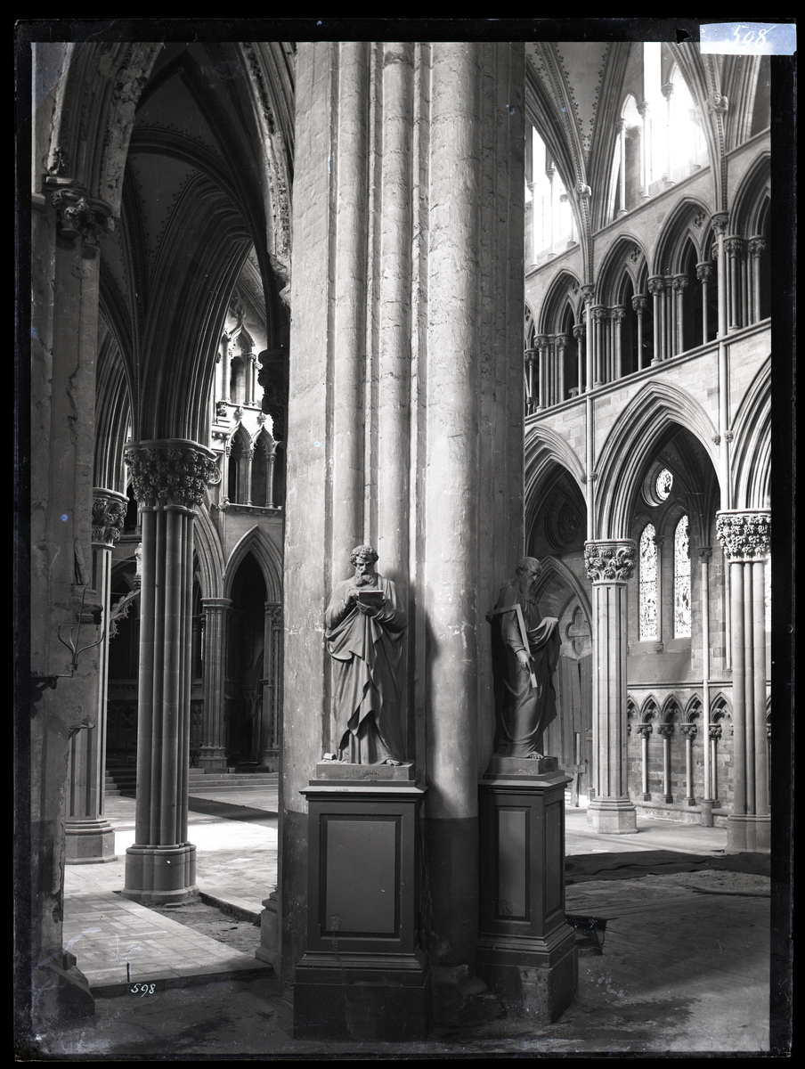 Koret i Nidarosdomen under restaurering. Her ser man at marmorgulvet legges. Bilde tatt fra tverrskipet mot sør-øst. To apostelskulpturer i gips fra oktogonen (utført av Hans Michelsen).