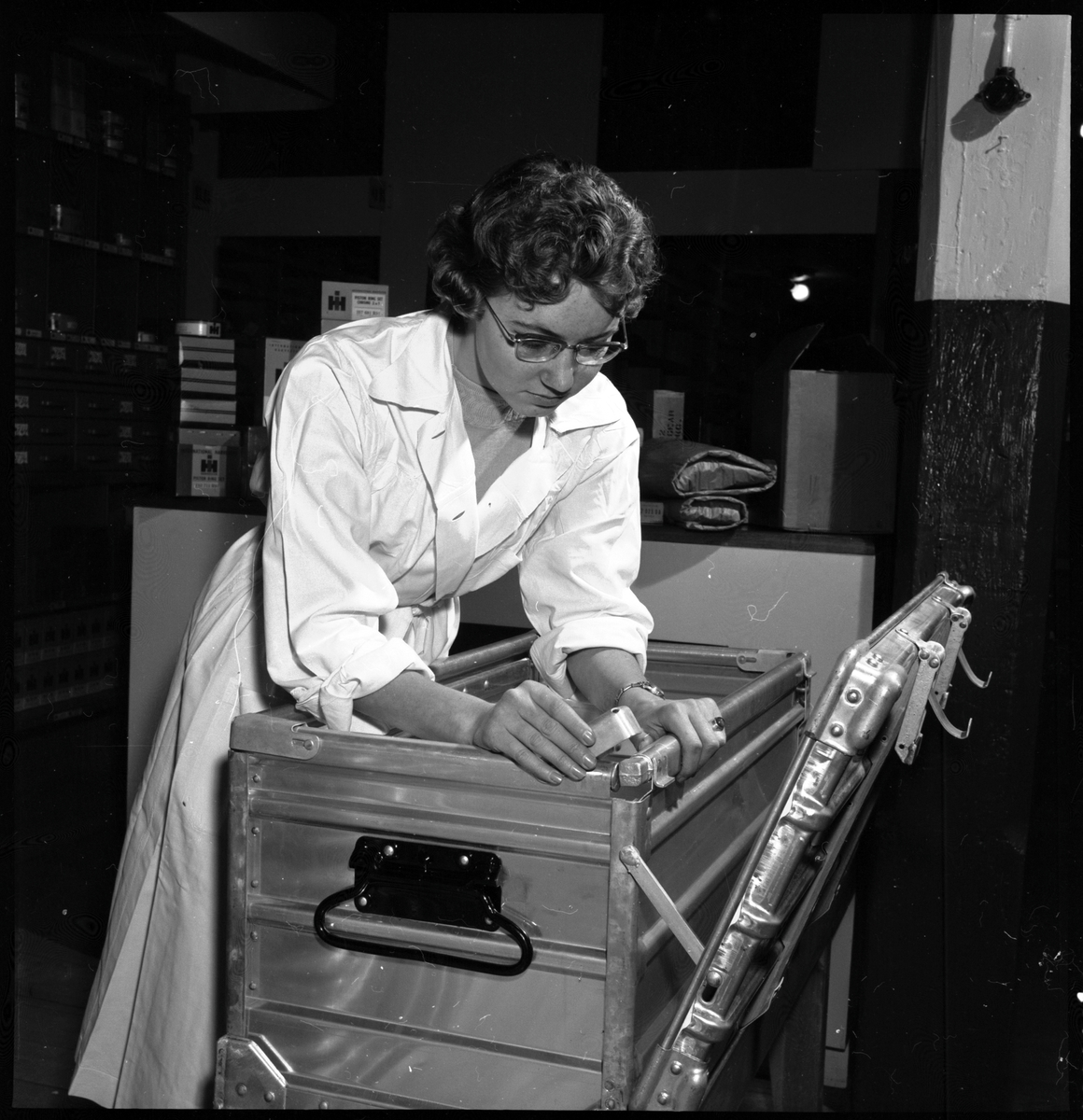 Kvinna instruerar hur man monterar småbehållare SJ La 10386, hopfällbar box av plåt.