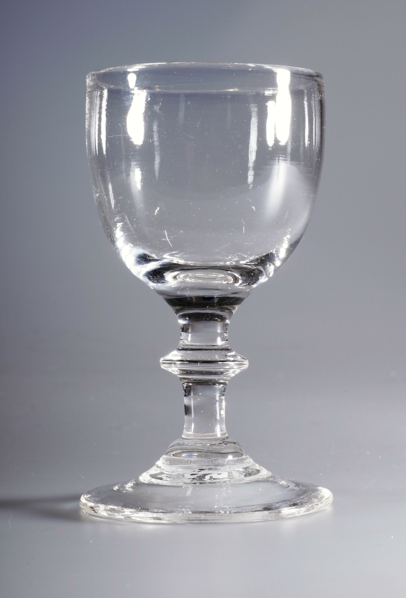 Stettglass, blåst i tre deler, med klokke, stett med skive og konveks fotplate. Brutt pontemerke/puntelmerke under. Kan være blåst på Gjøvik glassverk (1807-1843)