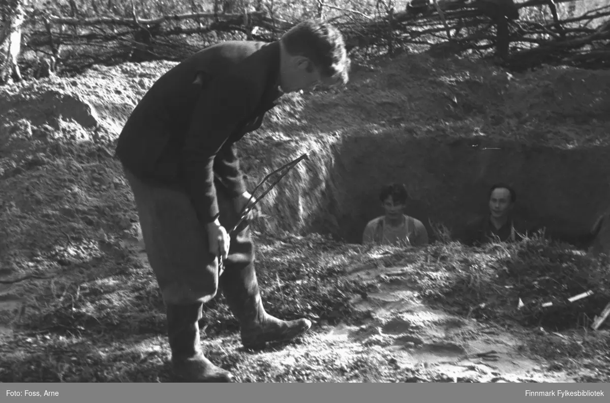 "Ingolf Ellila går med ønskekvist på Birkestrand. Fant vann uten problemer. Gravde like dypt som lengden. Han gikk mens kvisten bøyde seg 90 grad (rett ned)". Gjenreisningsarbeid foregår i Tanadalen, august-september 1946.