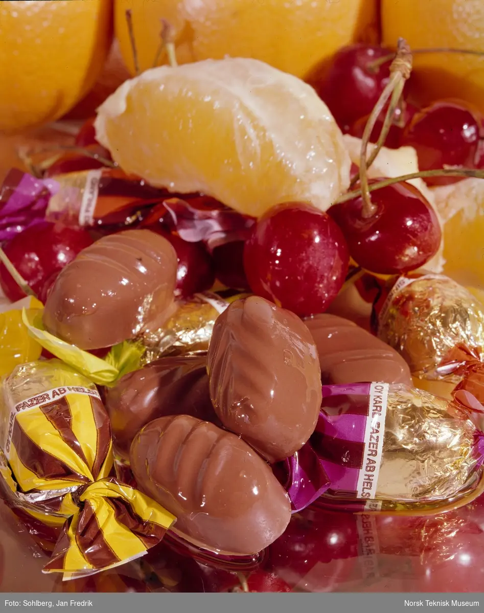 Reklamefotografi for konfektsjokolade. Sammen med sjokoladen er det lagt kirsebær og appelsinbåter tiil dekorasjon.