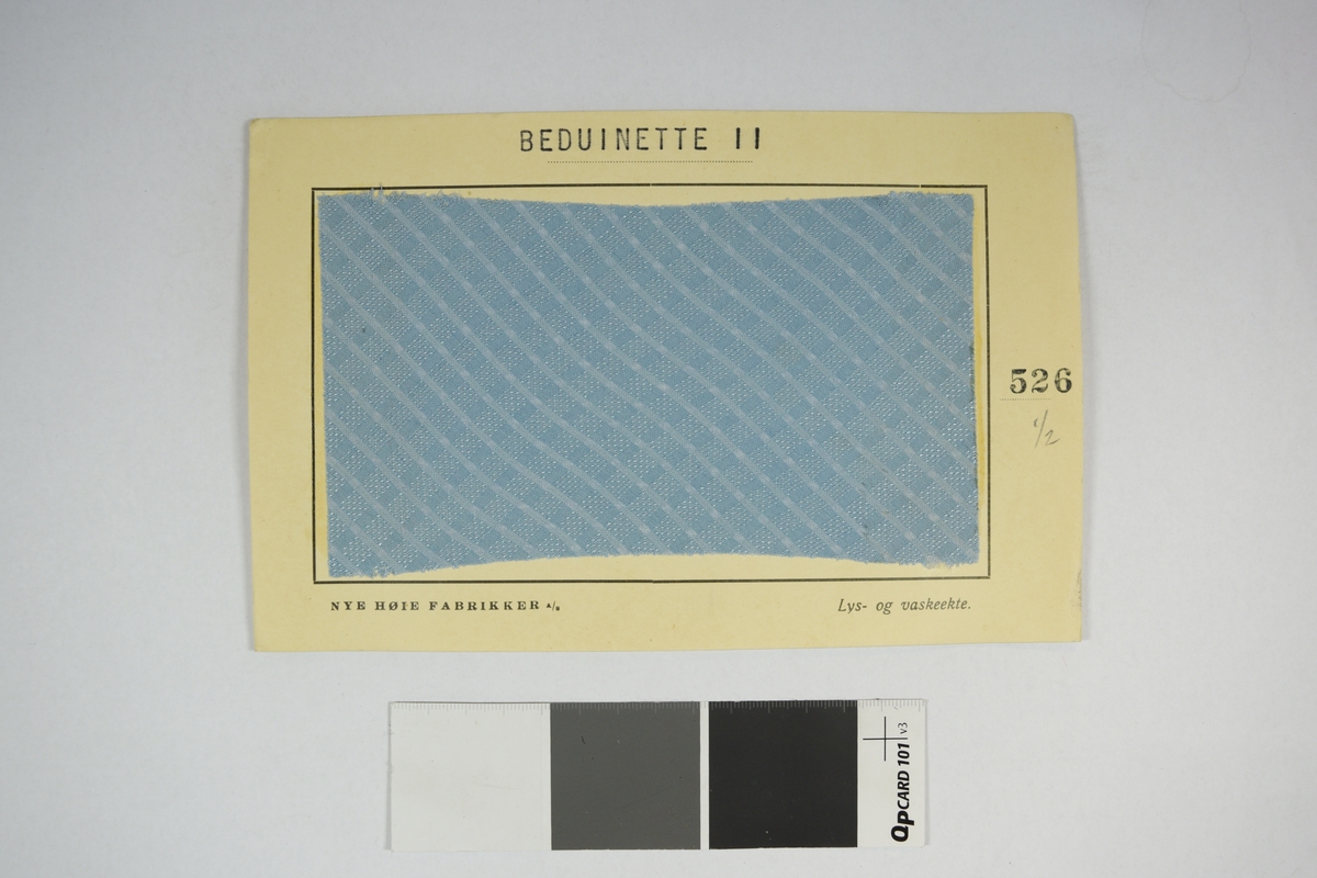 Prøvekort bestående av tekstilprøve limet til et papirkort. Rutete mønster.
