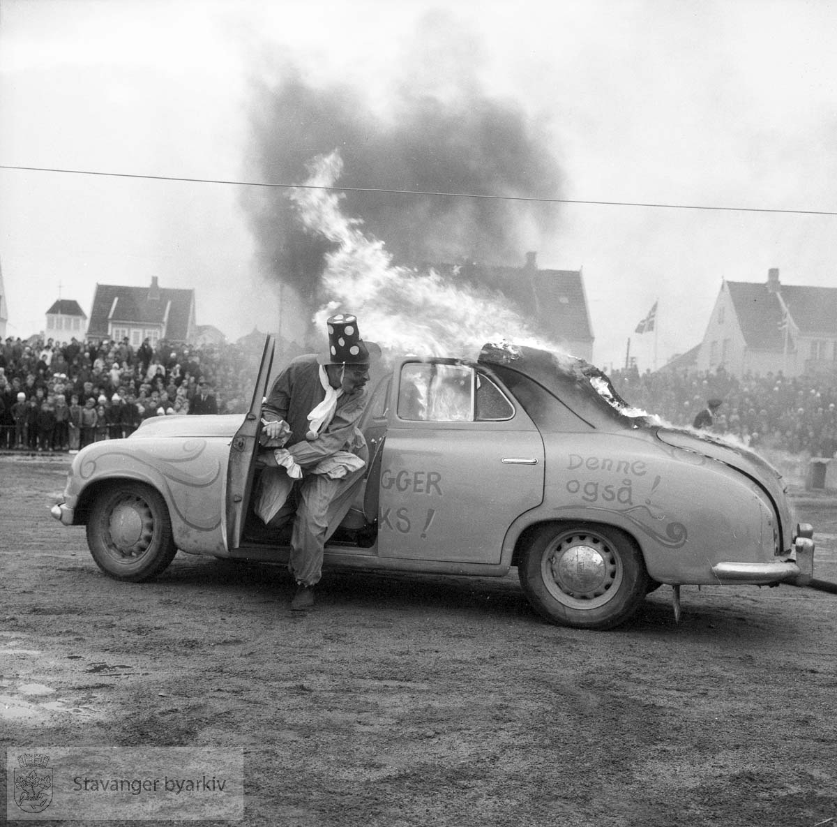 Oppvisning av gammelt og nyere materiell. Karl Jørgensen i klovnedrakt kjører en brennende bil.