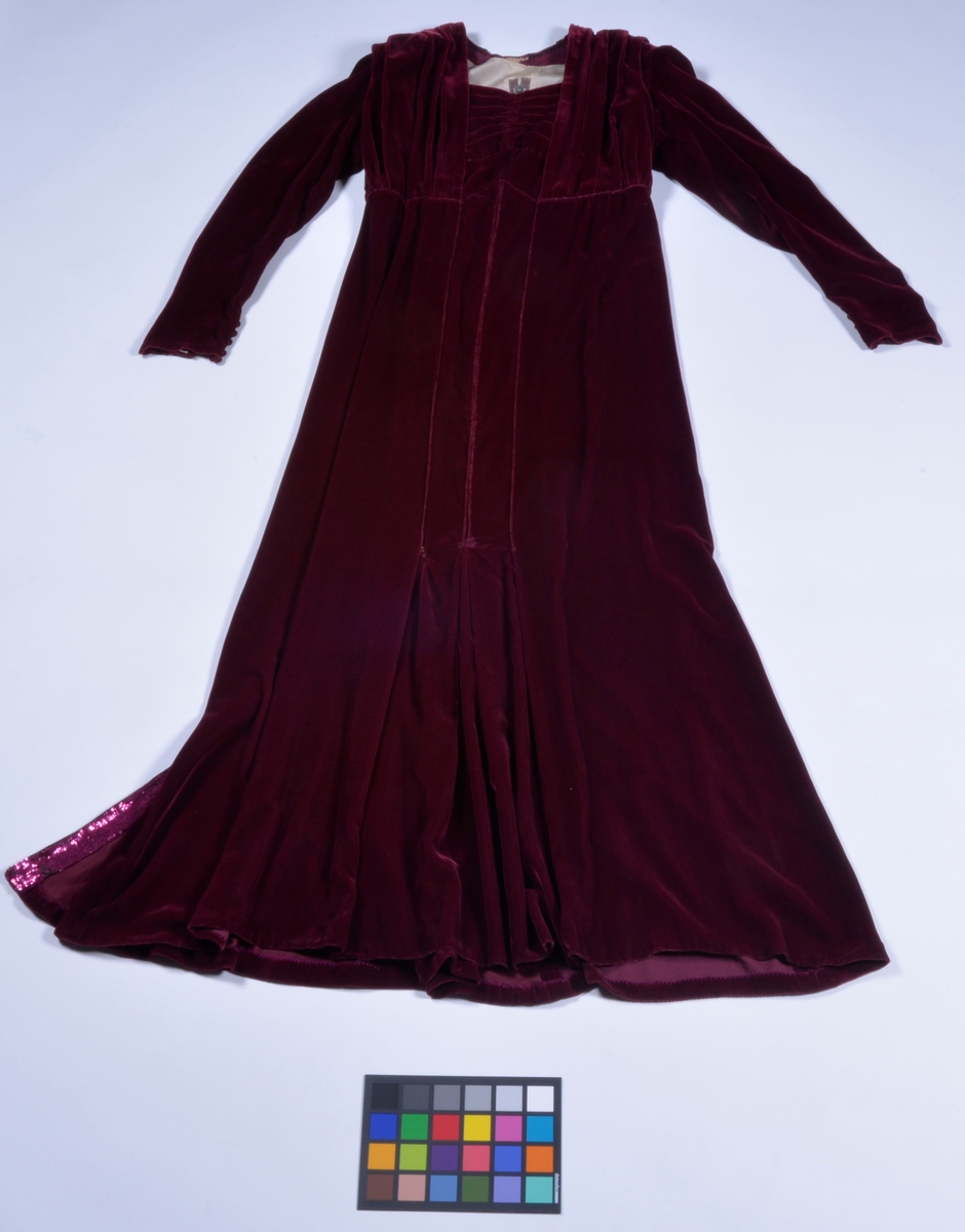 Lång festklänning av vinröd silkesammet med paljettbesättning i ryggen och på axlarna. Lång ärm.