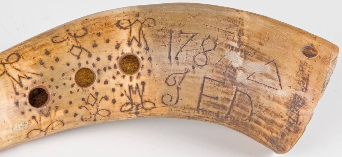 Vallhorn, av oxhorn, med tre ljudhål på sidan, ornerad kring ljudhålen och märkt 1784, I. E. D.