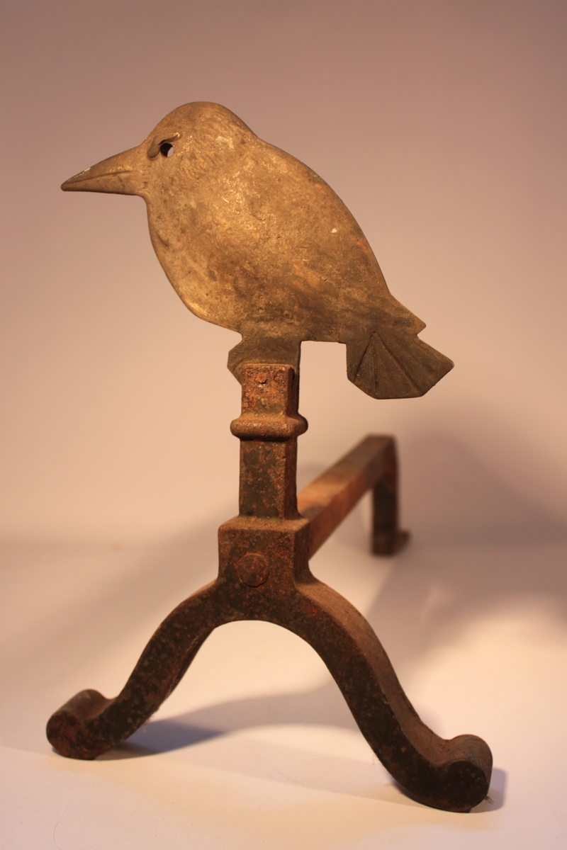 Eldhund för kakelugn med dekoration i form av en sittande fågel med stor näbb.