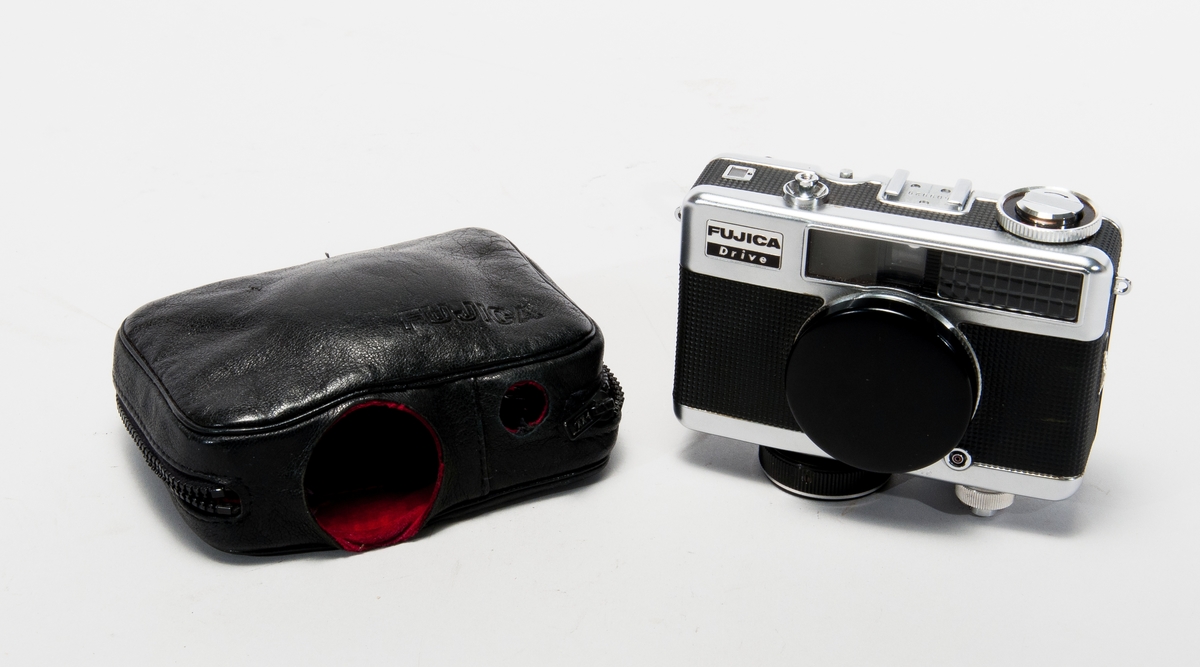 Småbildskamera Fujica Drive, med mekanisk winder, linslock. 
I blixtlåsförsett fodral av konstläder, nr 609929.
Objektiv och slutare: Seikosha-L, Fujinon 1:2,8 f=2,8 cm.
