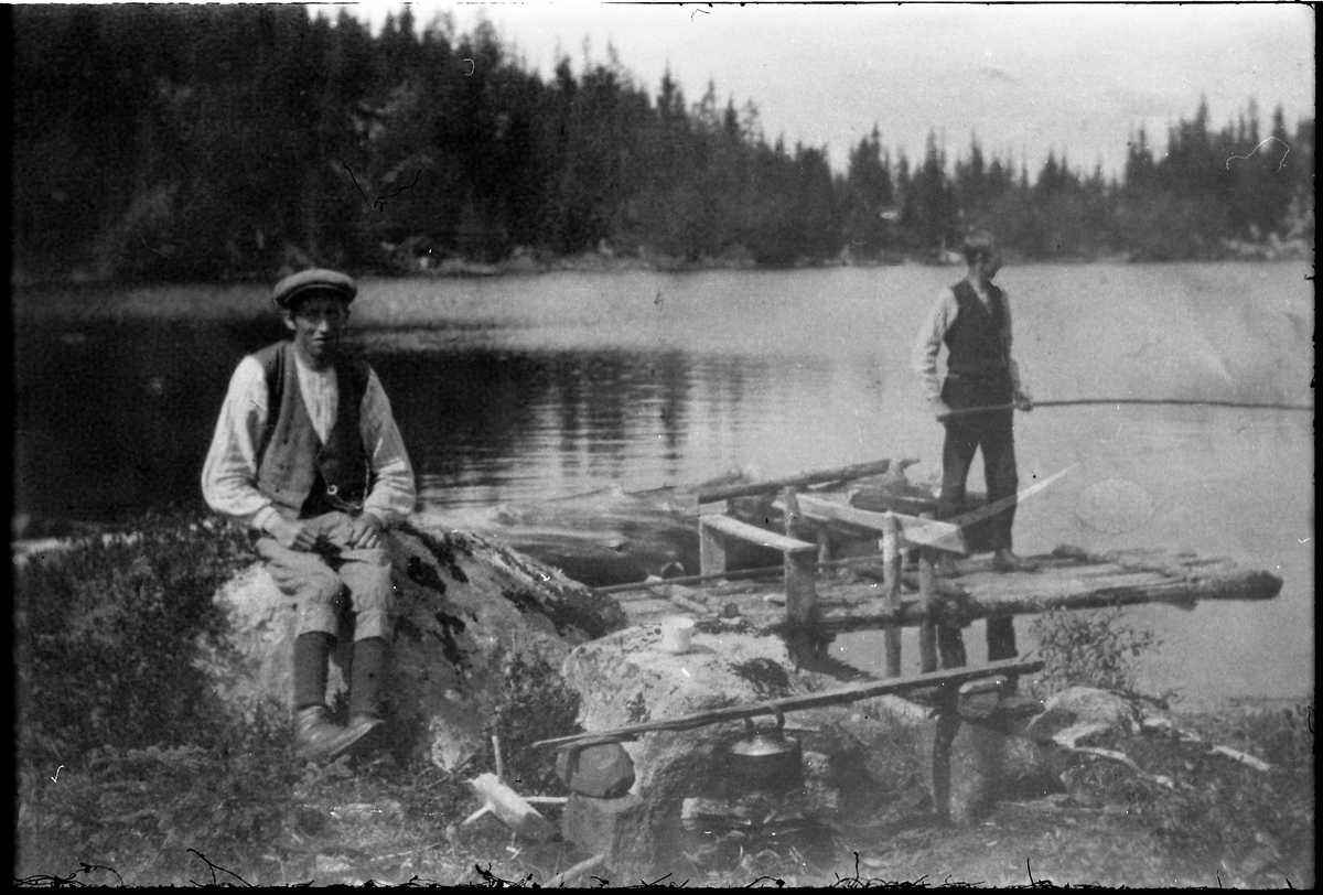 Avfotografert bilde av to menn ved et tjern. Den ene fisker. Hverken personer eller sted er identifisert.