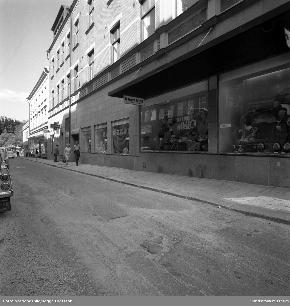 Gatuvyer på Torggatan norrut vid Forum, HEA hälso- och sjukvårdsbutik (H.E. Adamsson) samt en frisör.