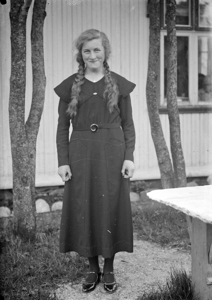 Leirfjord. Fotografi av Aslaug Nilsen Holmvik (Kvamme). Mulig konfirmasjonsbilde. Hun har mørk kjole og løstflettede fletter på hver side.
