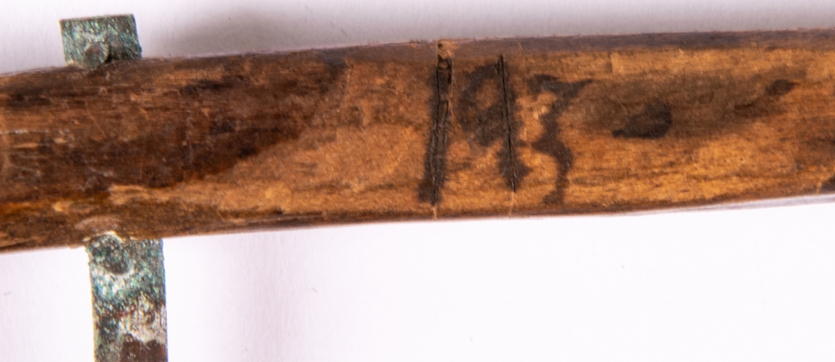 Passare av trä försedd med metallstift längst ned i ena benet. Ristade märkningar: LSD 1815 HH.