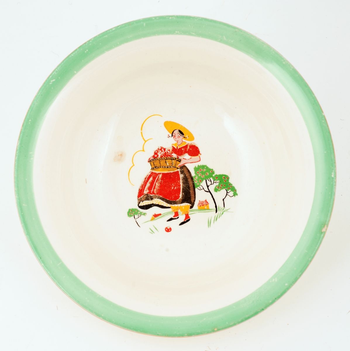 Dyp, hvit tallerken med grønn munningsrand, jentefigur-med-fruktkurv-motiv.