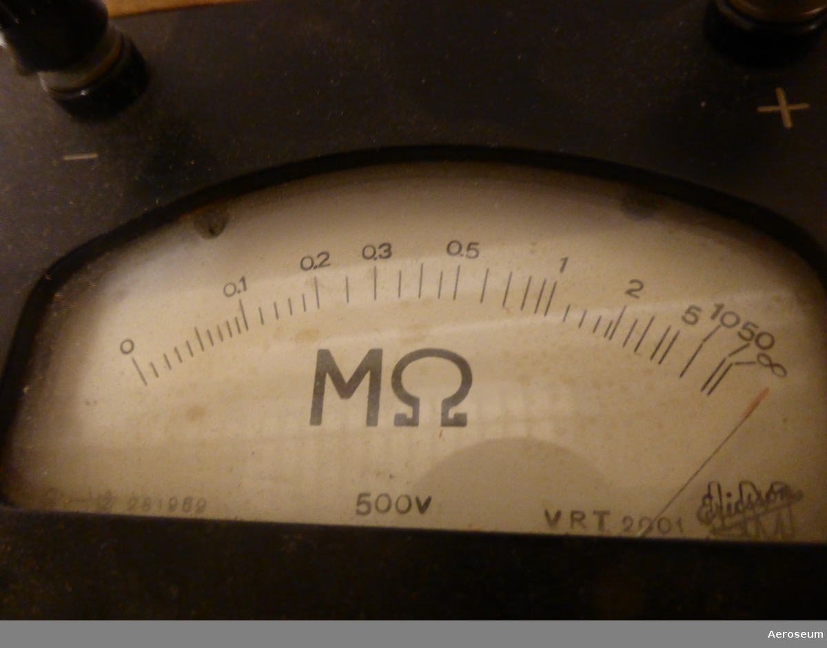 En ohmmätare i lackerat trähölje. Tillverkat av L M Ericsson. Märkt med "[tre kronor] Tc21050". Display: "L M Ericsson".
