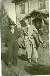 Petter Sinnerud og Hans Engnestangen stående utenfor et hus 