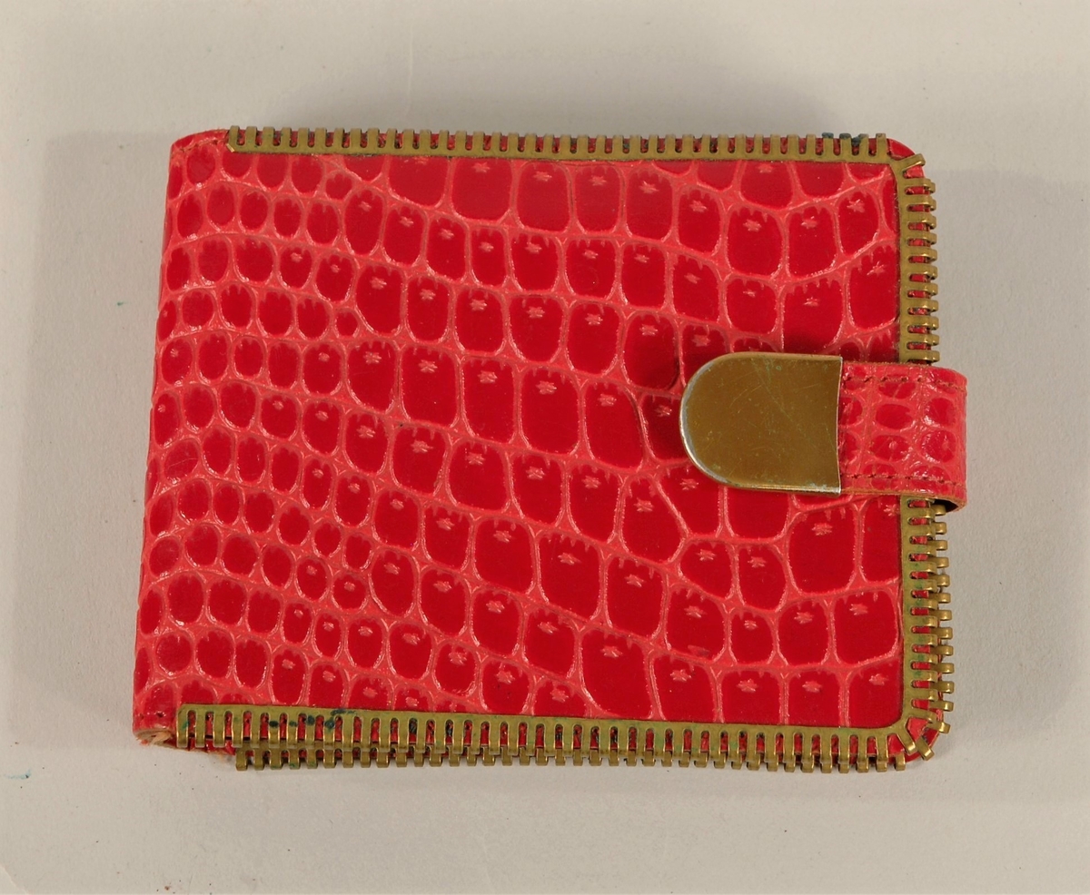 Lommebok med slangeskinnmønster. Trykknapp på remse for lukking. Plastlommer for oppbevaring inne i lommeboka.