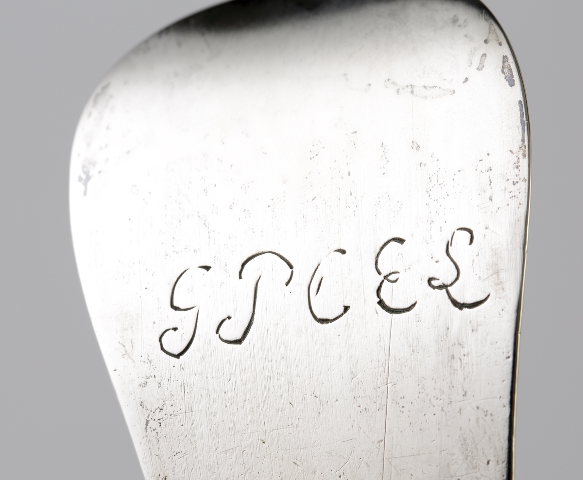 Ragusked i silver.
Slät modell med ås. Ägarinitialer på skaftets baksida "G.P.C.E.S.". Stämplar på baksidan av skaftet, tillsammans med åldermansranka.