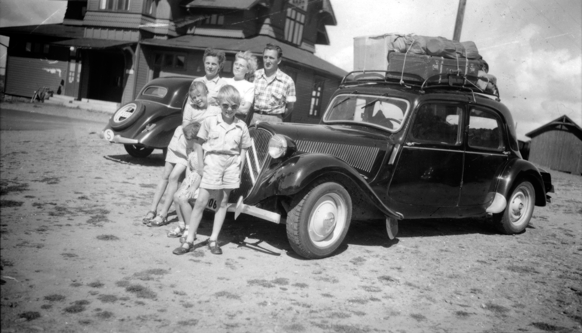En familj på semester vid bilen med packning på taket.