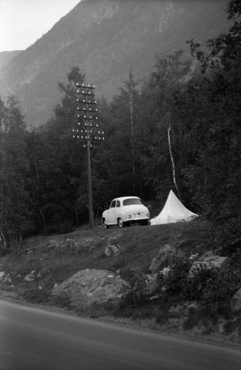 Teltslagning nærmest i vegkanten, trolig et sted i Gudbrandsdalen. Bilen tilhører Ole Majer, så her er nok han og Sigurd Røisli på tur.