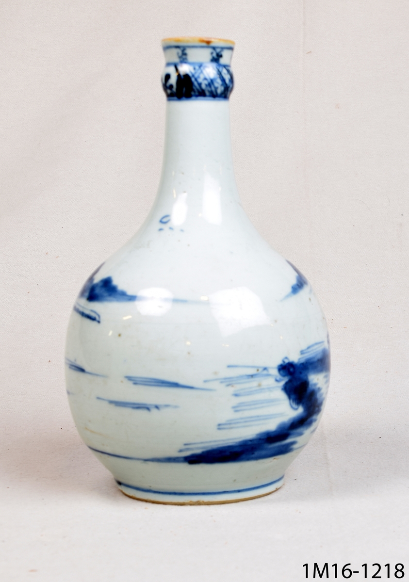 Rund vas i flaskform eller rund karaff med vit glasyr och blå handmålad dekor bland annat föreställande landskap. Kinesisk.