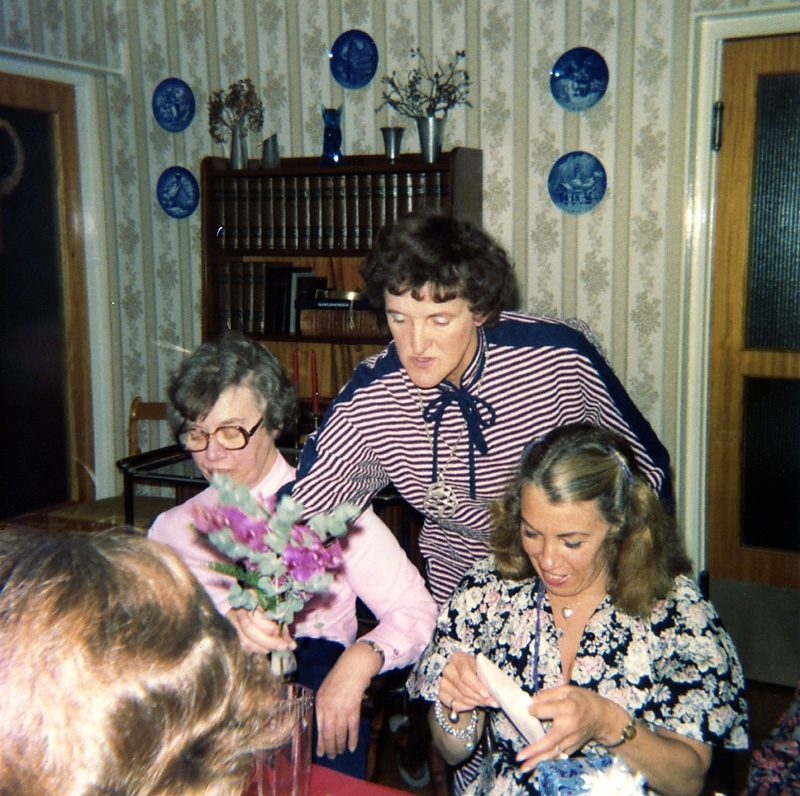 Maj-Britt Reimers sätter blommor i en vas, Brattåshemmet 1970-tal.
Från vänster: 1. Inga Svanberg, personal i köket. 2. Maj-Britt Reimers, vårdbiträde. 3. Inga-Britt Berntsson, vårdbiträde.
