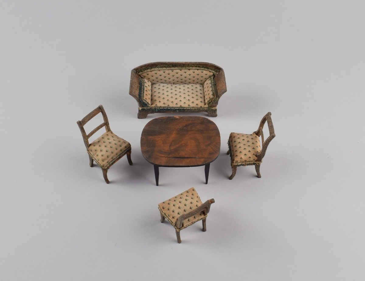 Gruppe av møbler til dukkehus bestående av en sofa, et ovalt bord og tre stoler.