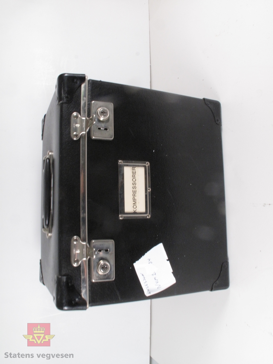 Én av seks kasser med opplæringsmateriell. Kassen består av informasjon om "Kompressorer". 
Kassen er svart og er laget av tykk kartong og kan låses med to "koffertlåser". Et håndtak på lokket.