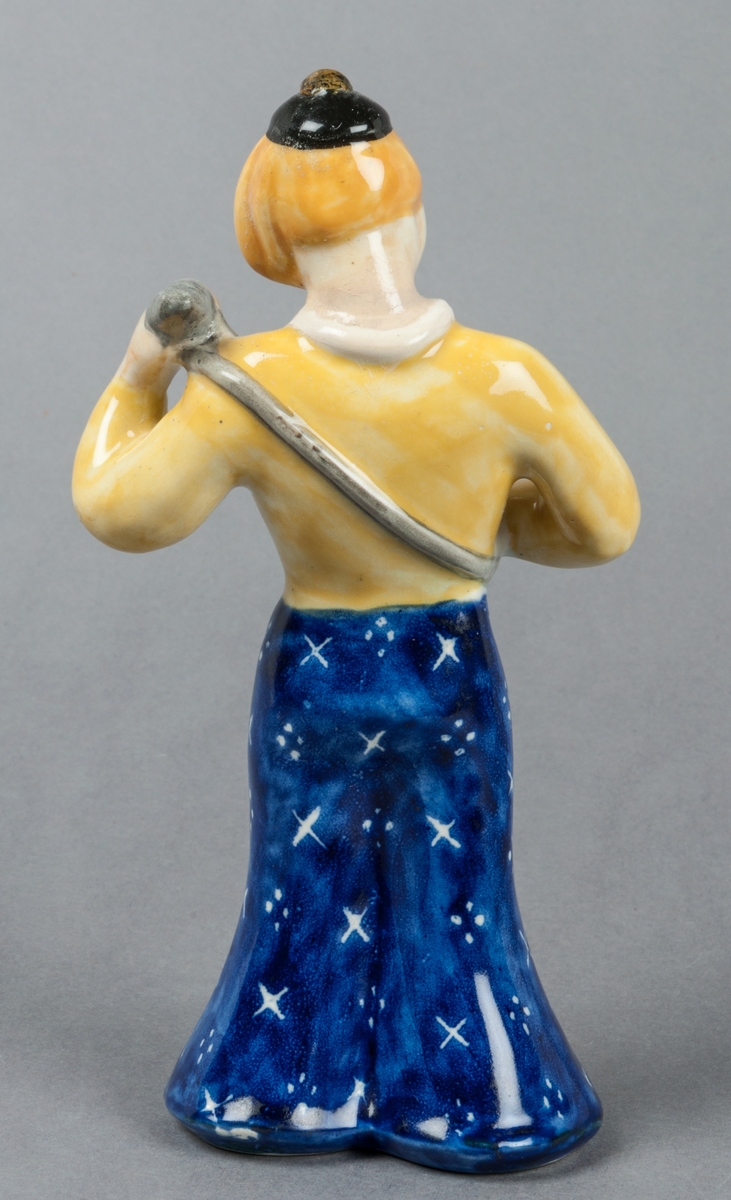 Figurin Zahra, kvinna spelande mandolin, glaserad i främst gult och blått. Tillverkad av Gefle Porslinsfabrik, formgiven av Märta Willborg 1937.