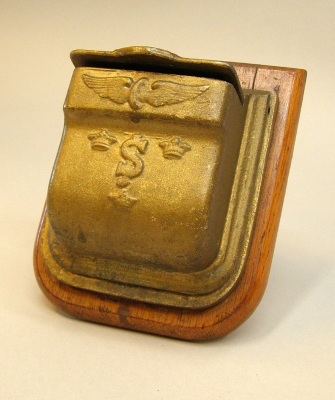 Tre askkoppar med lock, för vägghängning i kupéer. Askkopparna är guldmålade, och dekorerade i relief med SJ:s logga, ett bevingat hjul och tre kronor.