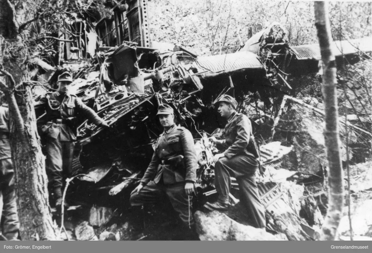 Tre soldater står ved et restene av et fly som har styrtet. 