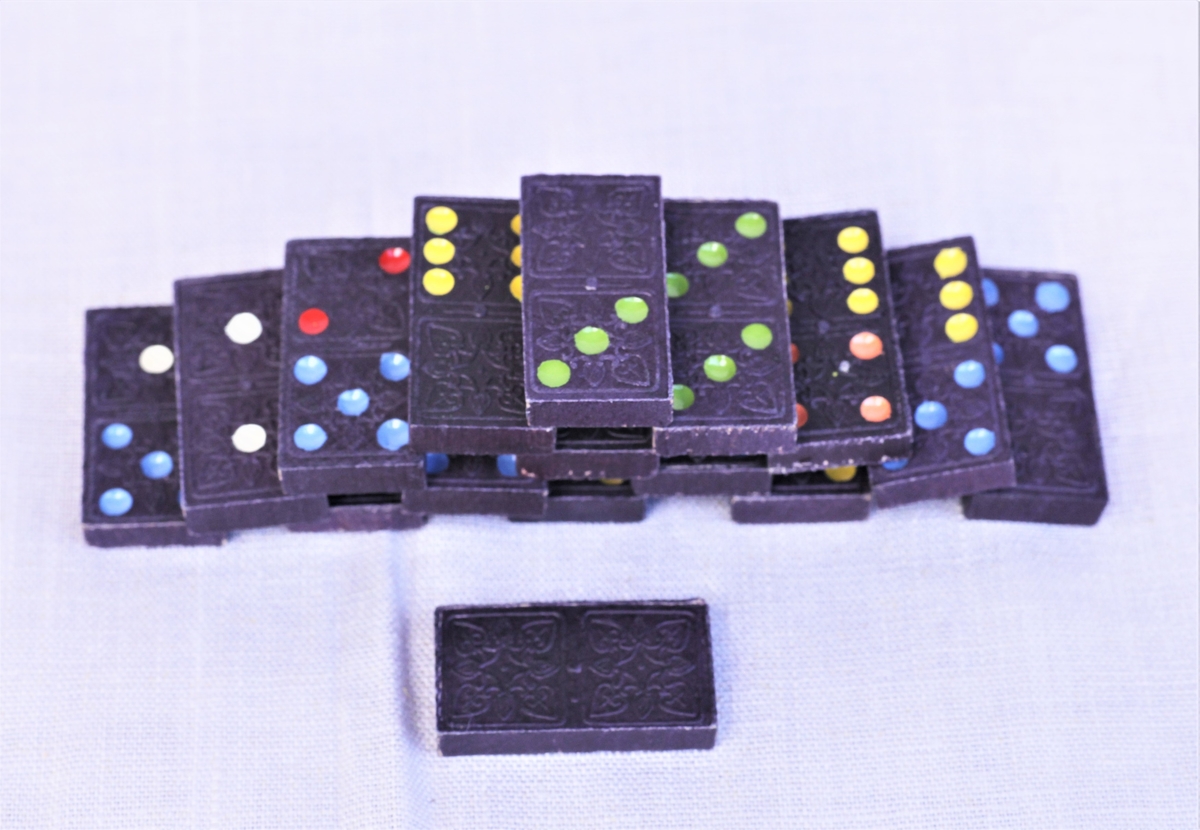 Dominospill med svarte brikker dekorert med en tiger på baksiden. Forsiden har ulike farger for de ulike verdiene (antall prikker).