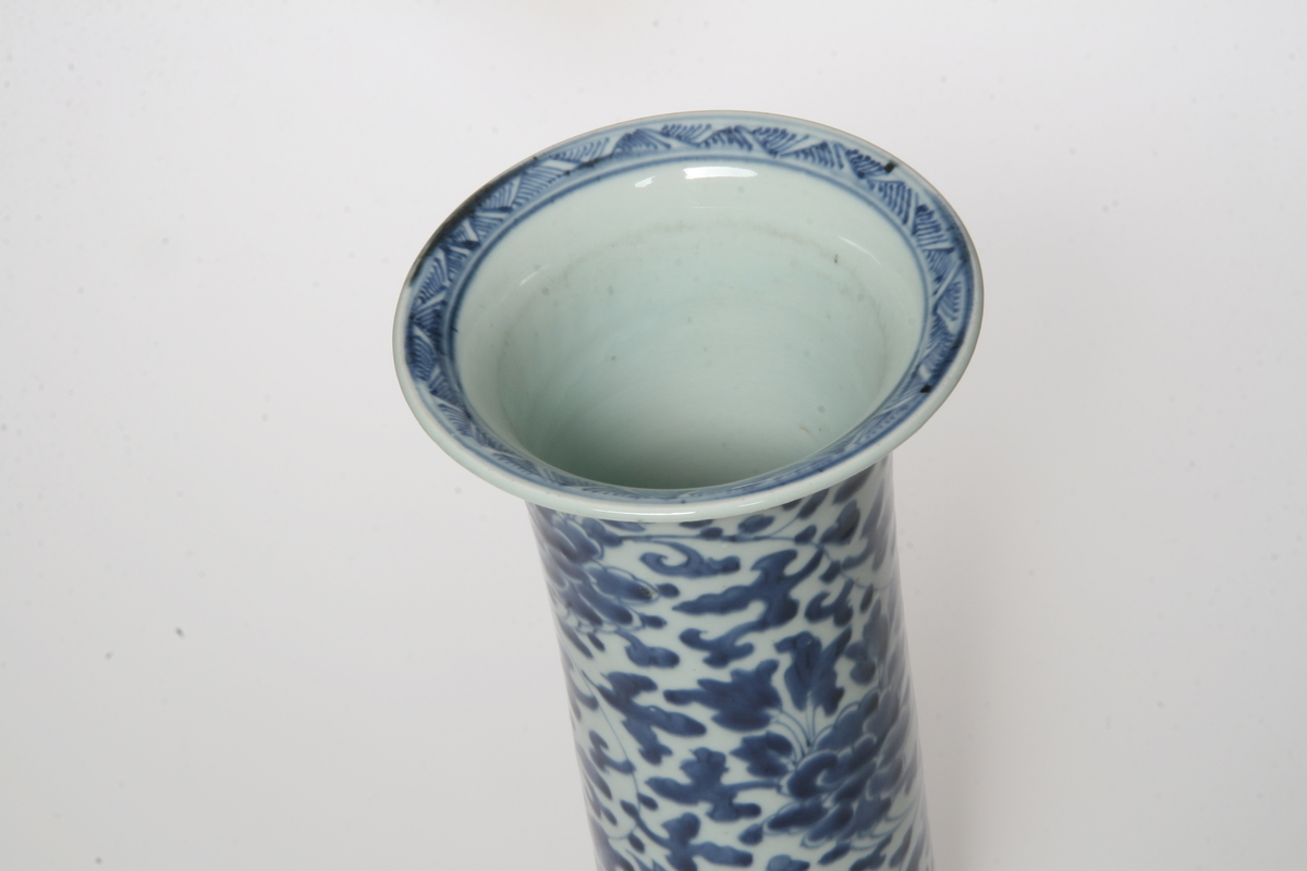 Porselen, sylinderisk, utsvunget oppe og nede, mørkeblå blomsterranker på lyseblå bunn. Samme som AS.310601-AS.310602.