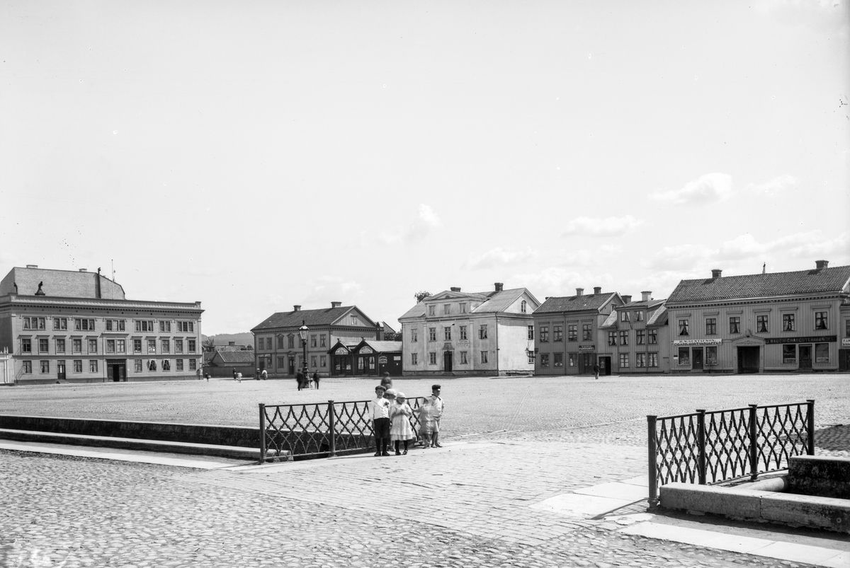 Södra sidan av Nya torget i Jönköping. Fastigheten till höger ägdes av charkuterist Joseph Bauer. I lägenheten en trappa upp föddes söndagen den 4 juni 1882 konstnären John Bauer. I de två låga gavelhusen låg Hilda Nordhs matvaruaffär. Till vänster i bild syns det så kallade Amerikahuset, byggt 1853, som var Erik Åkerhielms och hans hustrus första bostad i Jönköping.